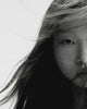 Black & white close-up video of a model with straight, shiny, dark hair blowing across her face.