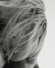 Black & white close-up of short, shiny hair blowing across a model's face